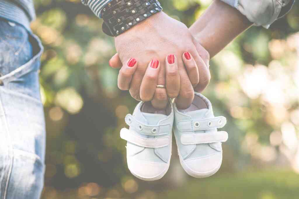 ידיים אוחזות בנעלי תינוק להודעה על ההריון