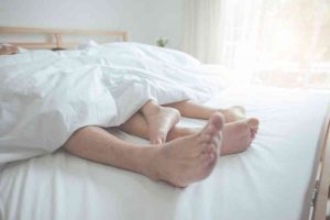 כפות רגליים של זוג בהריון במיטה