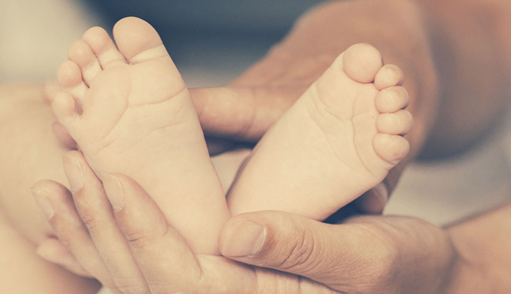 יד של מבוגר אוחזת ברגליים של תינוק