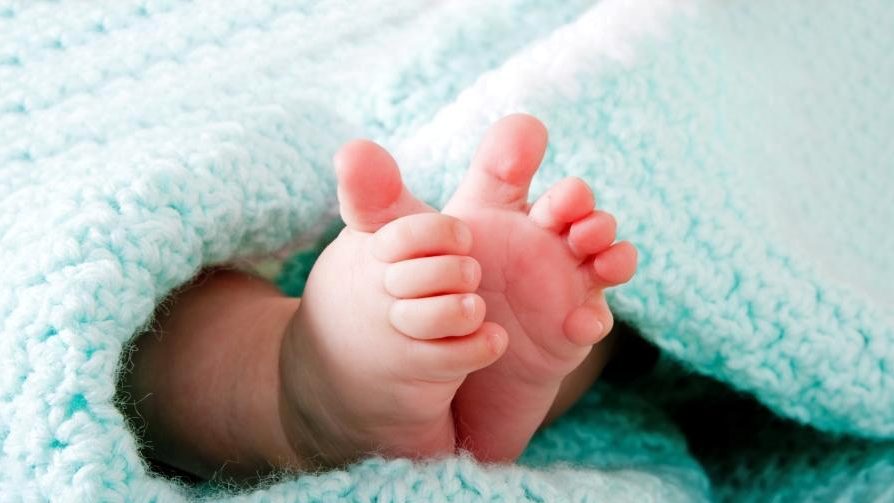 כפות רגליים של תינוק מציצות משמיכה